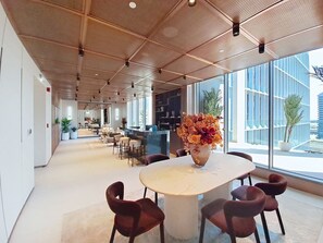 A modern interior with a large table, chairs, and a vase of flowers. - Premium Studio l near Museum of Future and Metro (Al Satwa)