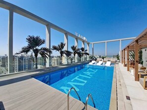 A rooftop pool with clear blue water, surrounded by palm trees and a city view. - Premium Studio l near Museum of Future and Metro (Al Satwa)