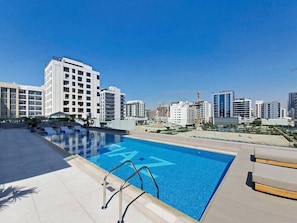 Una piscina en la azotea con vista a un paisaje urbano, rodeada de edificios modernos.