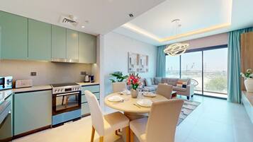 A modern kitchen with a dining area, a sofa set, and a large window with a city view.