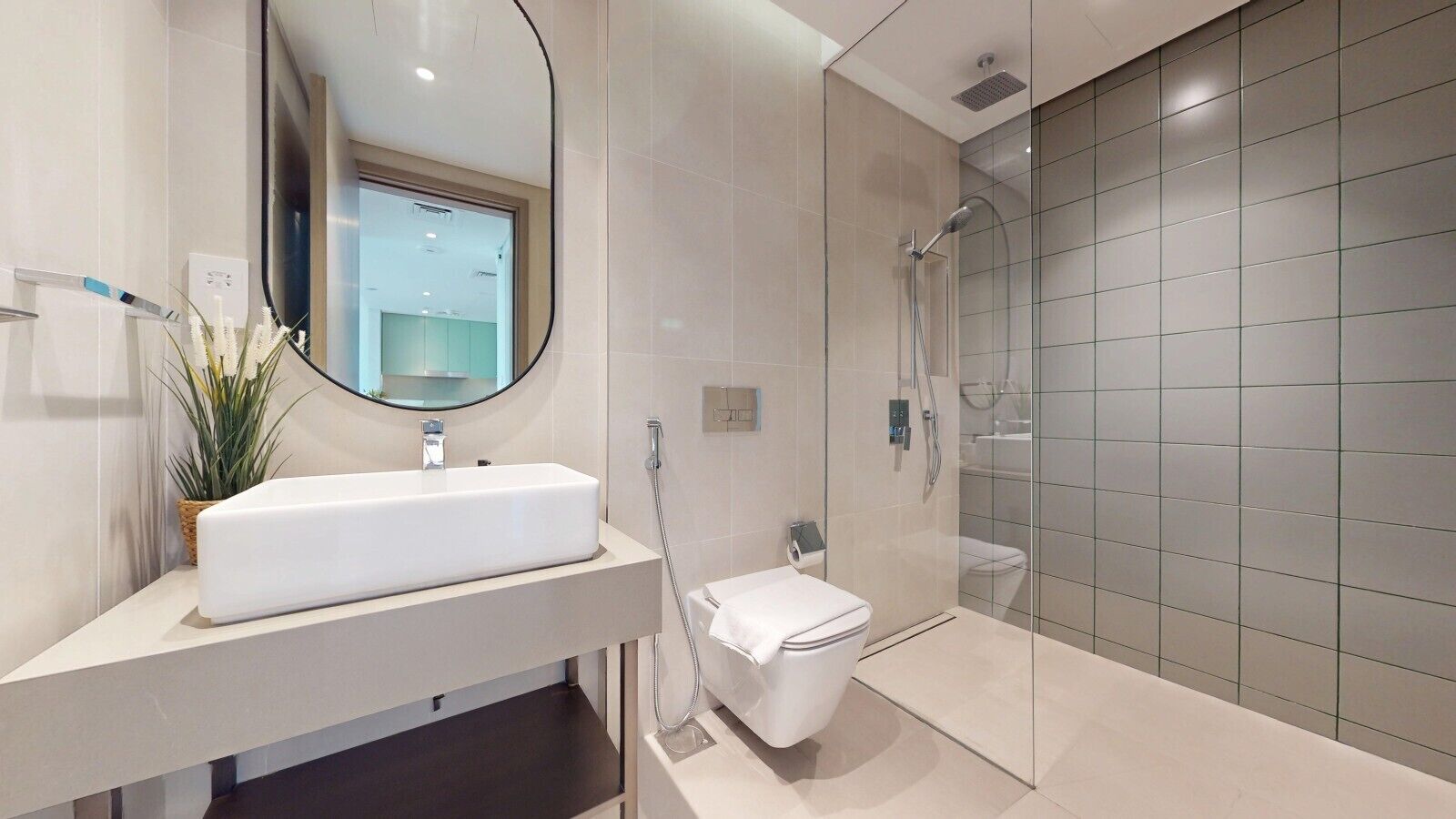 A modern bathroom with a white sink, a toilet, and a glass-enclosed shower.