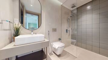 A modern bathroom with a white sink, a toilet, and a glass-enclosed shower.