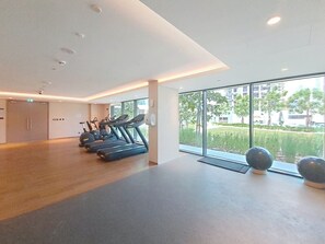 A spacious gym with treadmills, exercise balls, and large windows offering a view of greenery and buildings. - Luxurious 1 Bed l City Walk Mall, Coca-Cola Arena (City Walk)