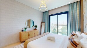 A modern hotel room with a large bed, a wooden cabinet, a round mirror, and a view of the city through a large window. - Luxurious 1 Bed l City Walk Mall, Coca-Cola Arena (City Walk)