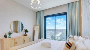 Una camera d'albergo con un letto grande, uno specchio rotondo, un armadio in legno e vista sulla città attraverso ampie finestre.