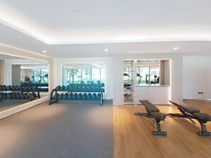 Ein Fitnessraum mit Trainingsgeräten, einem Spiegel und Holzboden.