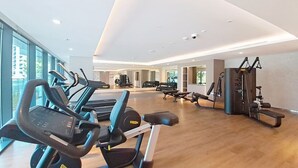 Una palestra con tapis roulant, macchinari per pesi e un ampio specchio.