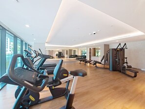 Ein Fitnessstudio mit Laufbändern, Kraftgeräten und einem großen Spiegel.