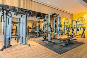 Uma academia com equipamentos de musculação, espelhos e uma parede motivacional.