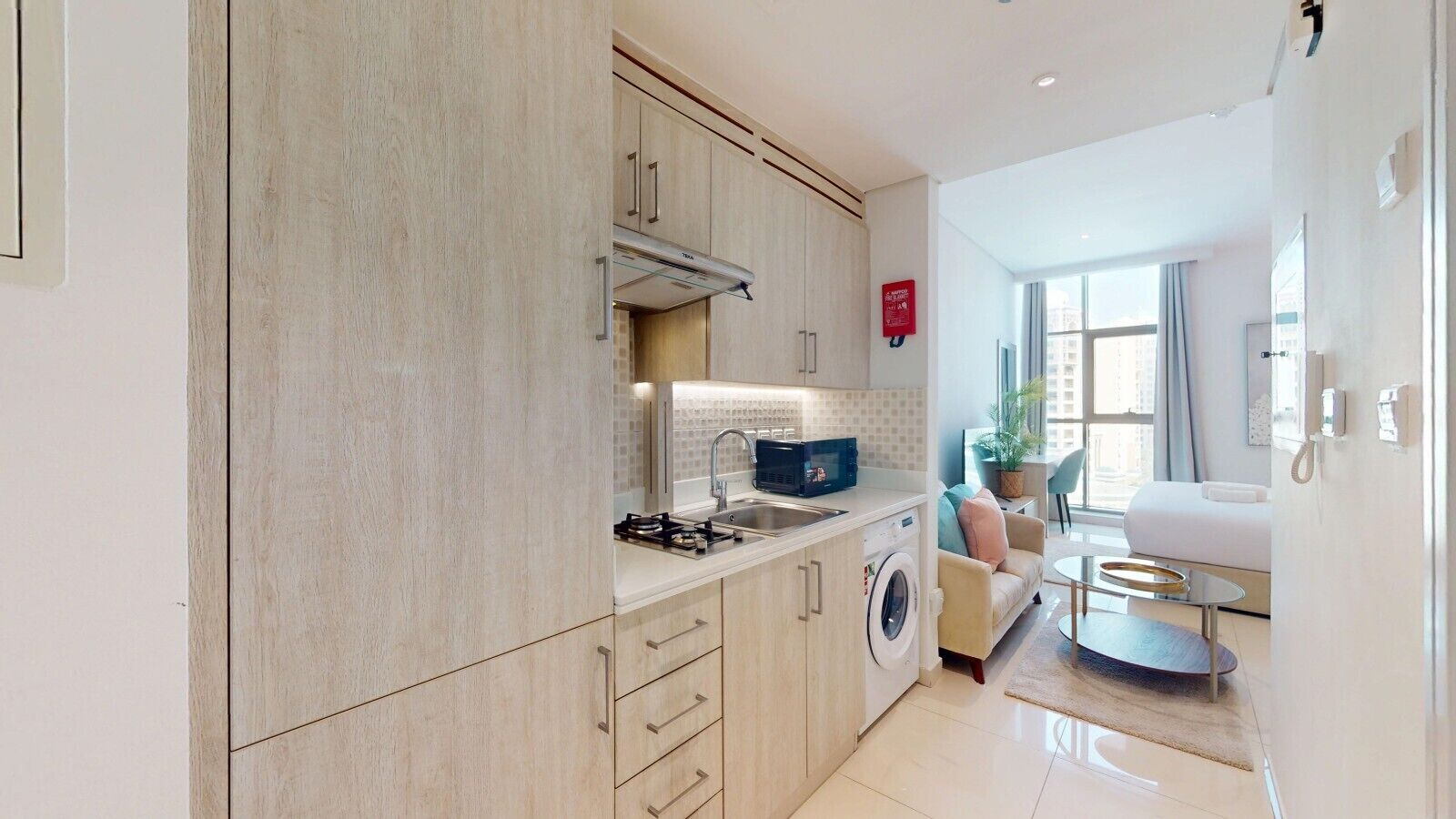 Una cocina moderna con lavadora, un comedor con sofá y mesa, y vistas a la ciudad.