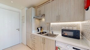 A modern kitchen with a microwave, sink, and cabinets. - Chic Studio in Palm l Pool & Gym (Palm Jumeirah)