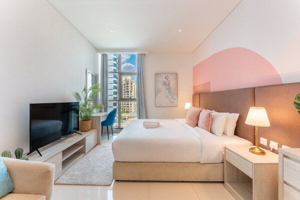 Une chambre d’hôtel moderne équipée d’un lit, d’une télévision, d’un bureau, d’une chaise et offrant une vue sur la ville.
