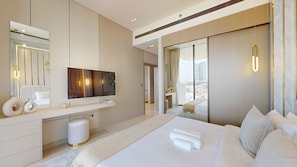 A modern hotel room with a large bed, a flat-screen TV, a desk, and a large window offering a city view. - Luxe 1 Bed with Private Pool l Tennis Court (JVC)