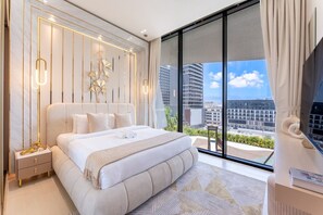 A modern bedroom with a large bed, a nightstand, a TV, and a balcony with a city view. - Luxe 1 Bed with Private Pool l Tennis Court (JVC)
