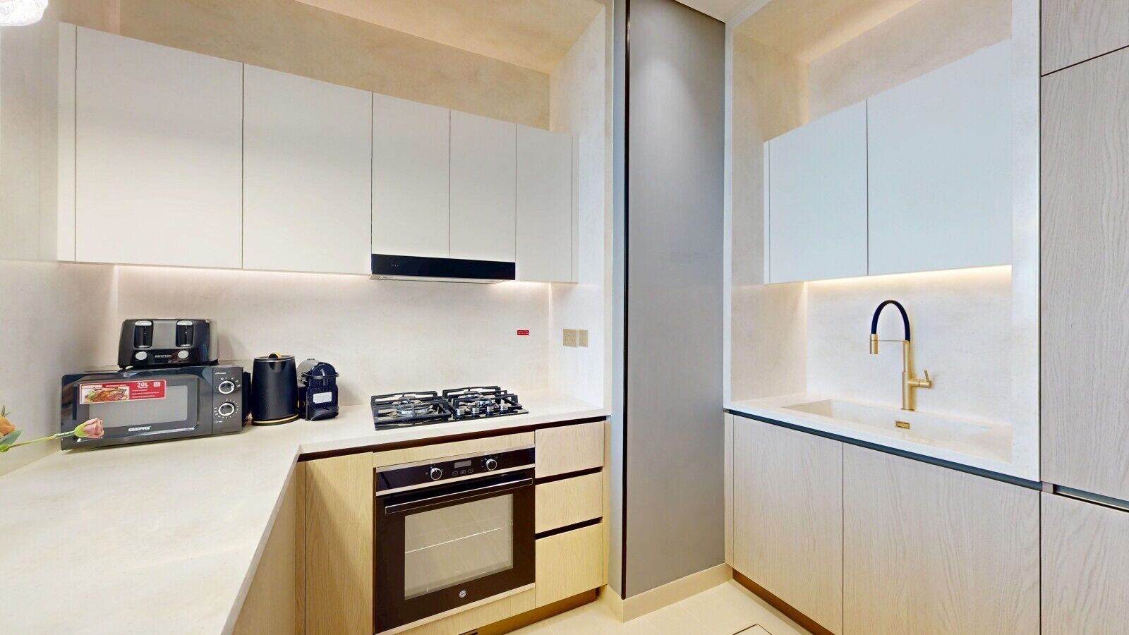 A modern kitchen with a built-in oven, microwave, and gas stove.