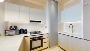 A modern kitchen with a built-in oven, microwave, and gas stove. - Luxe 1 Bed with Private Pool l Tennis Court (JVC)