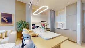 Una cocina moderna con una isla central, armarios blancos y una lámpara colgante.