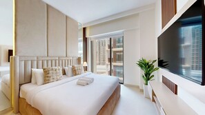 Habitación de hotel moderna con una cama grande, televisión y balcón con vista a la ciudad.