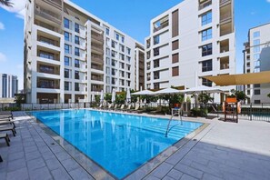 Un hotel moderno con piscina, varios balcones y zonas de estar al aire libre.