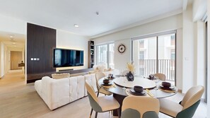 Una sala de estar moderna con televisor, sofá, mesa de comedor y sillas.