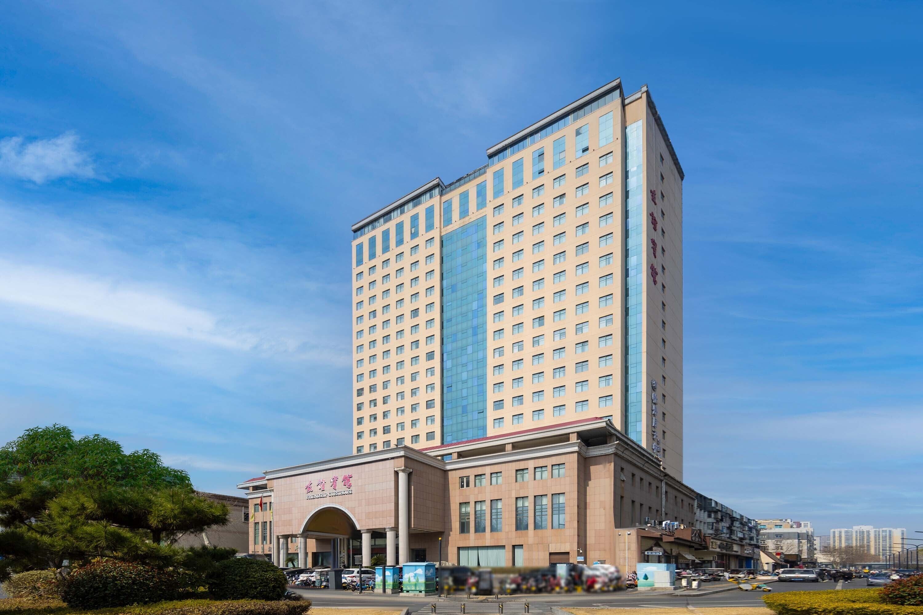 Un hotel moderno de gran altura con una entrada destacada, varios pisos y cielo despejado.