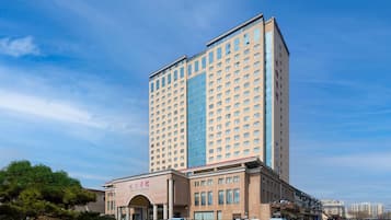 Un hotel moderno de gran altura con una entrada destacada, varios pisos y cielo despejado.