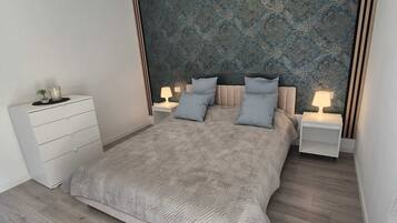 Ein modernes Schlafzimmer mit einem großen Bett, zwei Nachttischen, einem Beistelltisch und einer Wanddekoration.