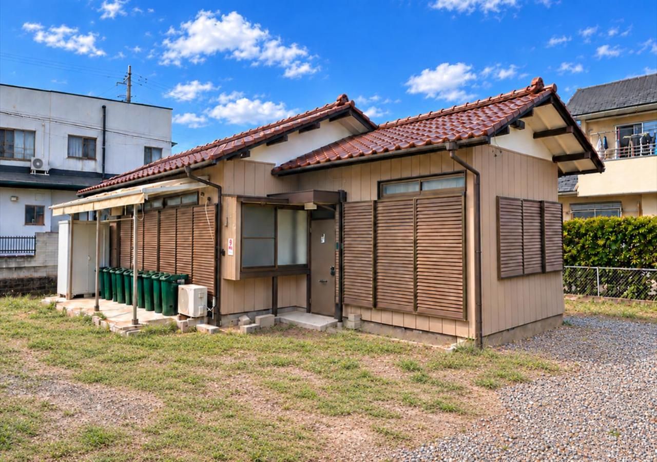 A small building with a tiled roof, a covered entrance, and a gravel driveway.