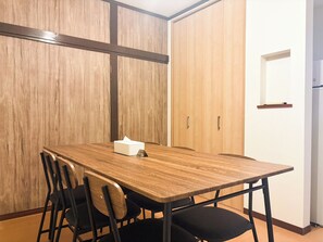 Ein Konferenzraum mit einem Holztisch, schwarzen Stühlen und einer weißen Papiertütenbox.