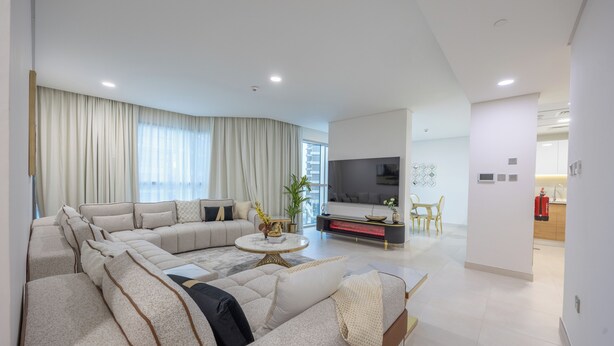 A modern living room with a sectional sofa, a coffee table, and a flat-screen TV. - Bloomfields 3BR - Radiant Viewz 2 - Reem (Abu Dhabi)
