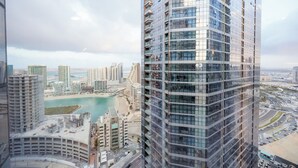 A high-rise building with a glass facade, a view of a coastal area with buildings and a beach, and a road network. - Bloomfields 3BR - Radiant Viewz 2 - Reem (Abu Dhabi)