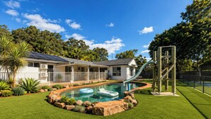 A residential property with a swimming pool, a slide, and a fenced yard.