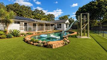 A residential property with a swimming pool, a slide, and a fenced yard.