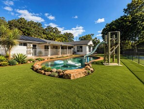 Una propiedad residencial con piscina, tobogán y patio cercado.