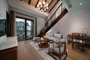 A spacious living area with a high ceiling, a staircase, and a balcony with a view. - Deqing Radisson Manor (Huzhou)