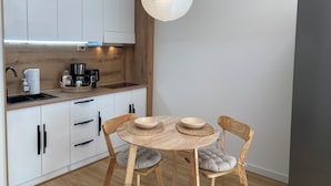 Cocina moderna con armarios blancos, encimera de madera, cafetera y lámpara colgante.