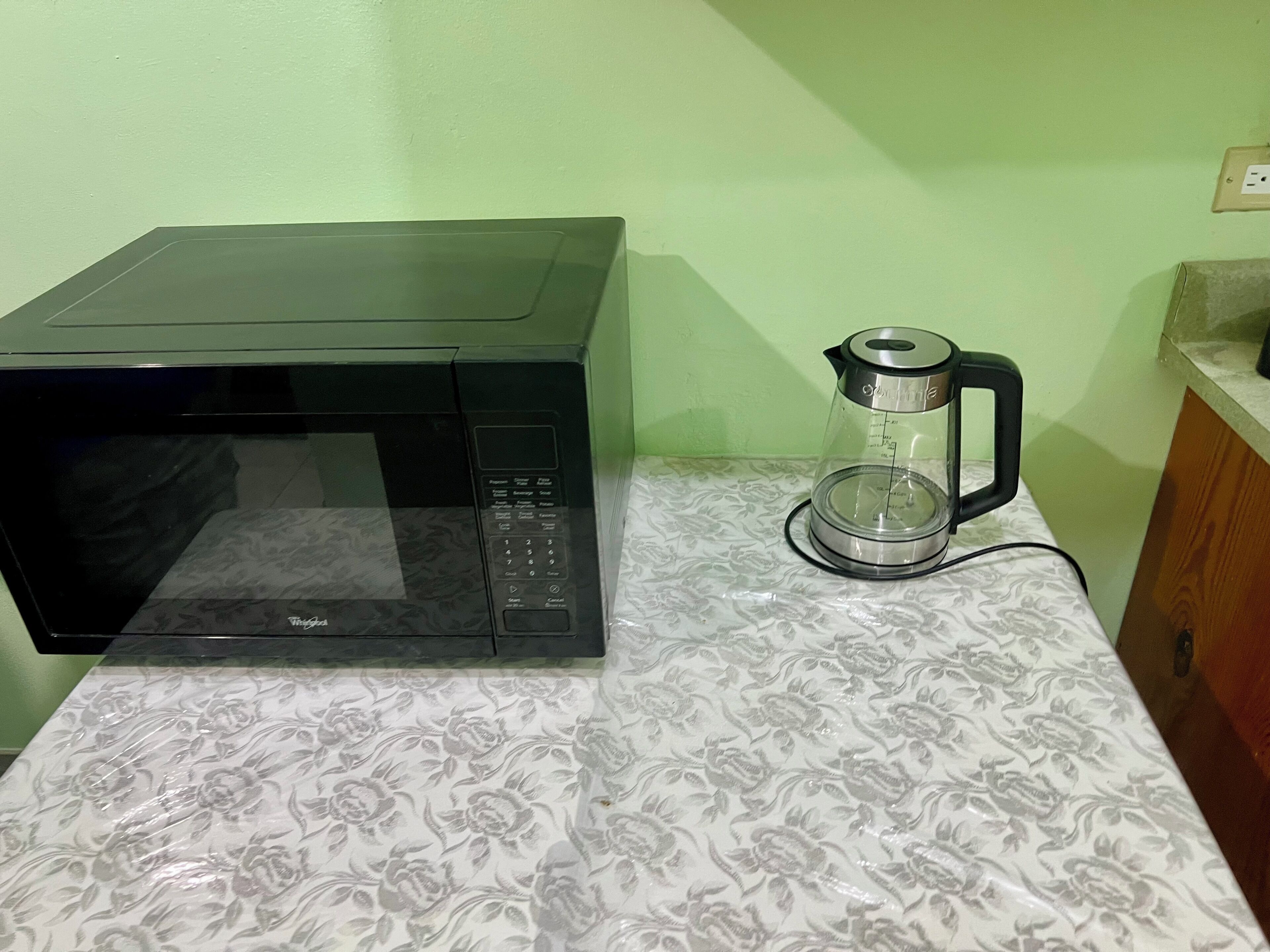 A microwave and a coffee maker on a patterned countertop.