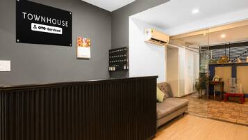 A reception area with a sign indicating it is a serviced townhouse. There is a sofa and a small table with decorative items.