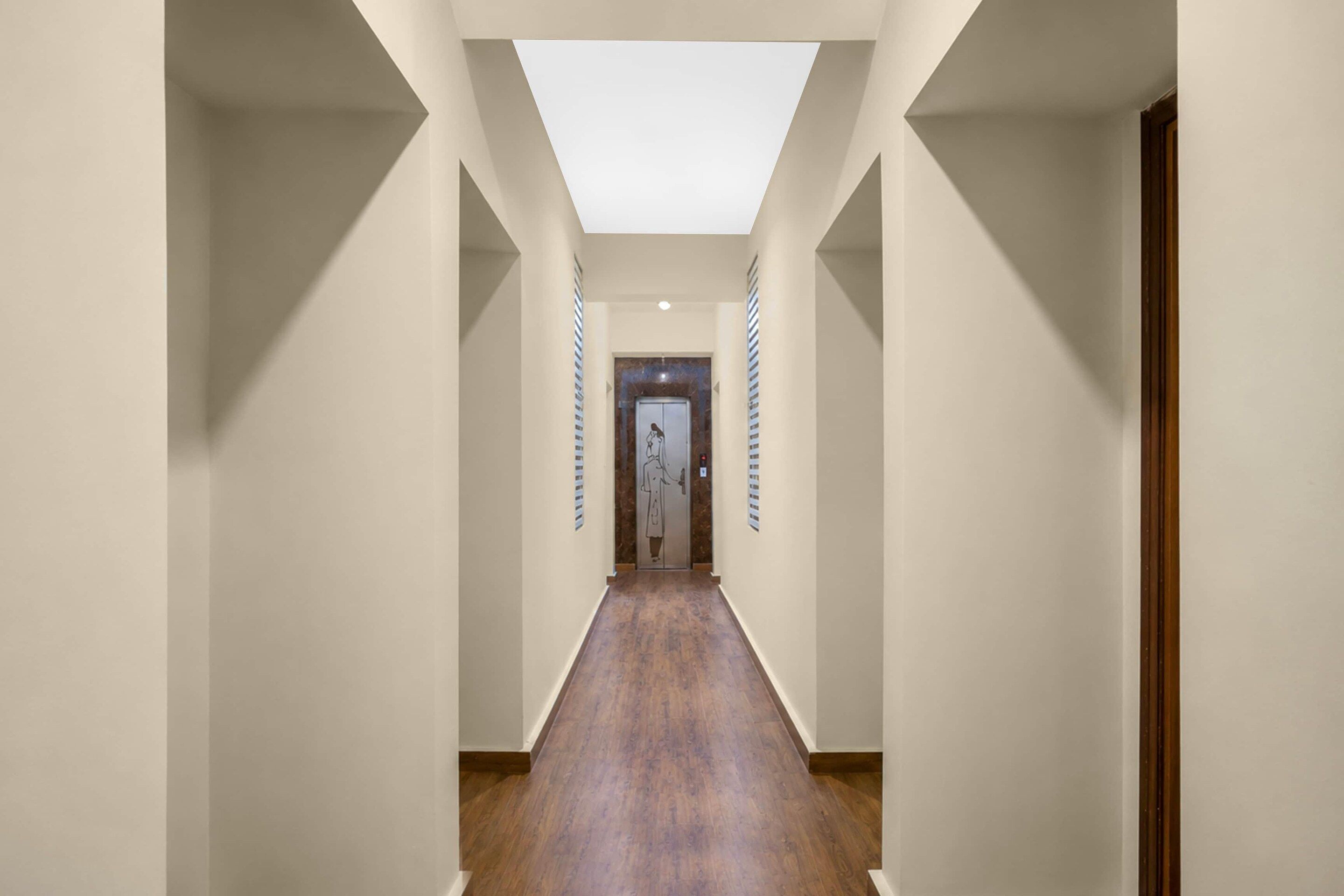 A long, narrow hallway with a skylight ceiling and wooden flooring.