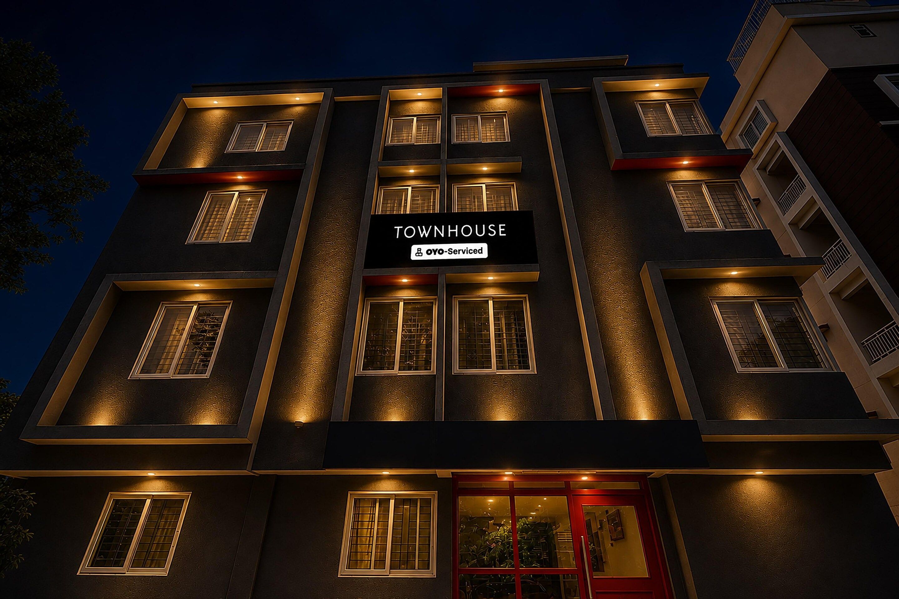 A multi-story building with a sign reading 'TOWNHOUSE' and 'Oyo-Serviced' indicating a serviced apartment.