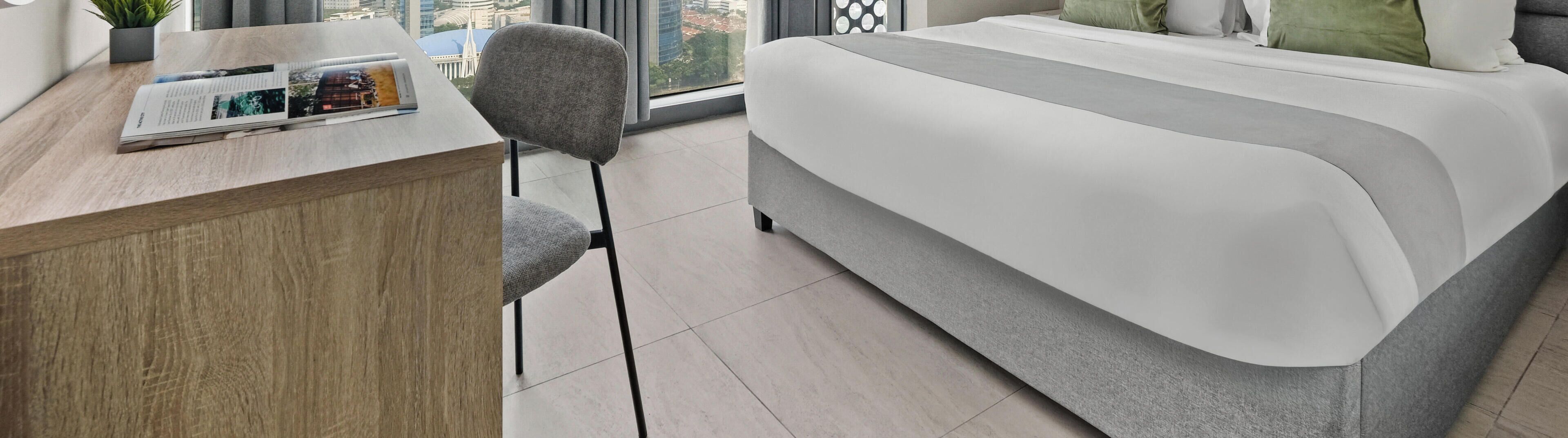 A modern hotel room with a bed, a desk, and a chair.