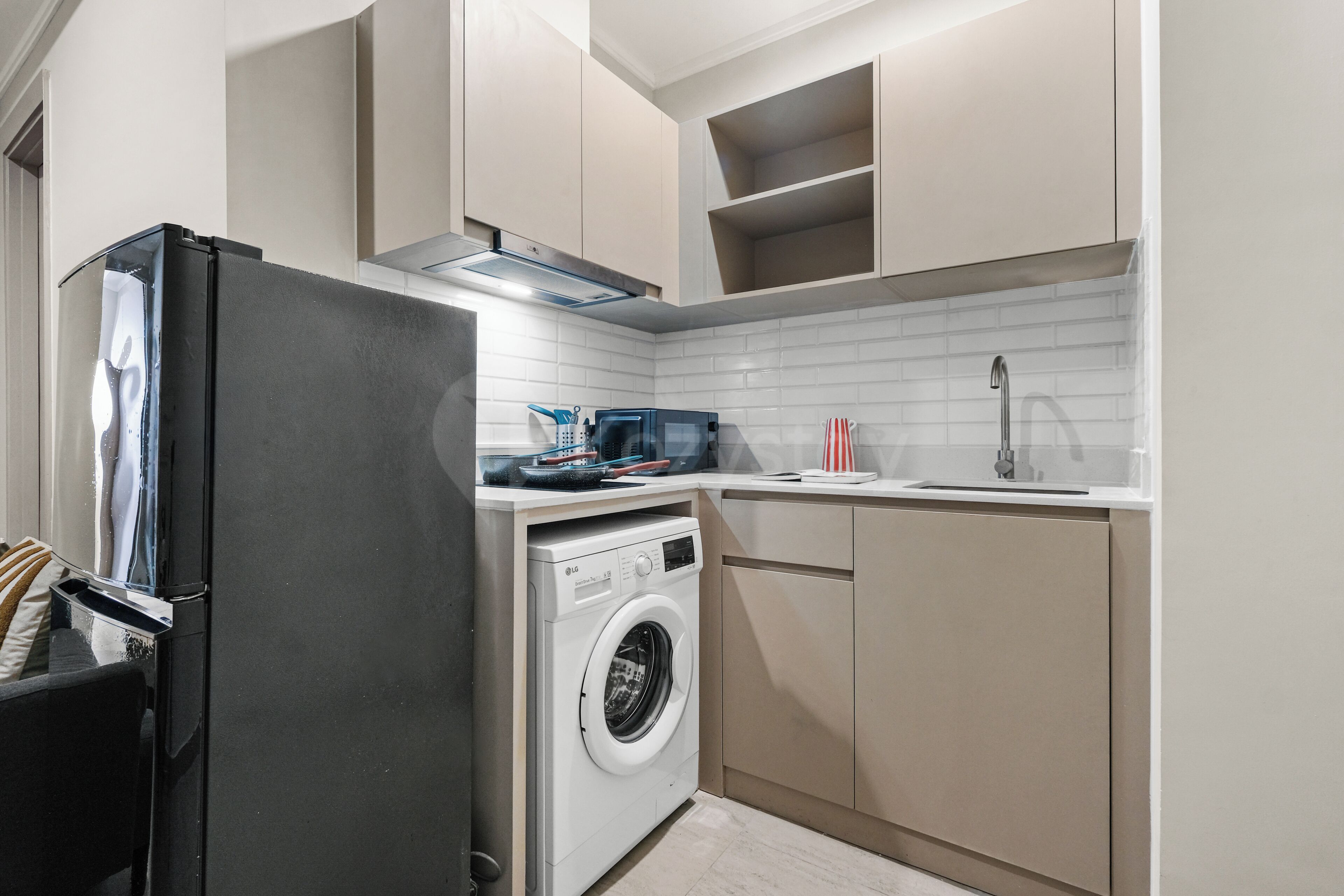 A compact kitchen with a washing machine, a microwave, and a refrigerator.