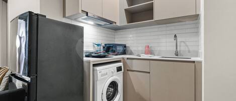 A compact kitchen with a washing machine, a microwave, and a refrigerator.