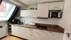 Una kitchenette compacta con pileta, microondas y alacenas.