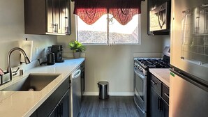 Een moderne keuken met donkere kastjes, een roestvrijstalen spoelbak, een fornuis en een koelkast.