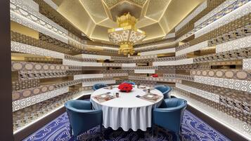 A circular table with blue chairs, surrounded by patterned walls and a chandelier.
