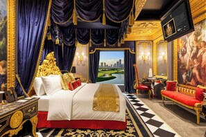 Una lujosa habitación de hotel con una cama grande, un sofá rojo, un escritorio y vistas a un paisaje urbano.