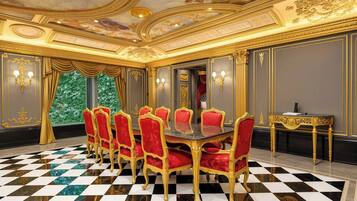A luxurious room with a checkered floor, a round table with red upholstered chairs, and ornate gold detailing on the walls and ceiling.