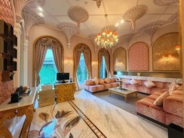 A luxurious living room with a marble floor, ornate ceiling, and a large chandelier.