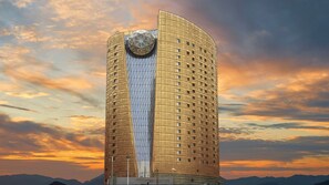 Un hotel alto y cilíndrico con una fachada de vidrio geométrica única y una estructura esférica distintiva en la parte superior.